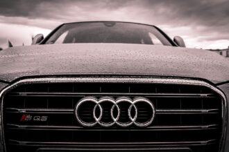 Αυτοκίνητο Audi στον δρόμο υπό βροχή με τον σήμερα της εταιρείας στον προφυλακτήρα
