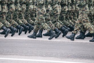 Στρατιώτες με στολή παραλλαγής βαδίζουν σε σχηματισμό σε στρατιωτική παρέλαση