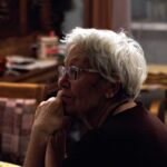 Ηλικιωμένη συνταξιούχος με γυαλιά είναι σκεπτική στο σπίτι της