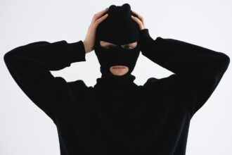 Νεαρός με στολή ληστή και κουκούλα πιάνει το κεφάλι του