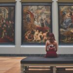 Γυναίκα παρατηρεί πίνακες ζωγραφικής σε μουσείο