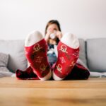 Κοπέλα τεμπελιάζει και χαλαρώνει στον καναπέ της με τα πόδια πάνω στο τραπέζι του σαλονιού