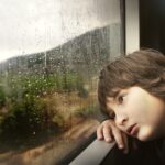 Μικρό αγόρι ταξιδεύει χαζεύοντας έξω από το παράθυρο του τρένου