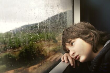 Μικρό αγόρι ταξιδεύει χαζεύοντας έξω από το παράθυρο του τρένου