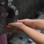 Child washing hands with soap at a kitchen sink for hygiene protection