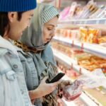 Woman checking food prices in a German supermarket aisle
