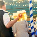 Visitors raising steins inside a decorated Oktoberfest beer tent in Munich