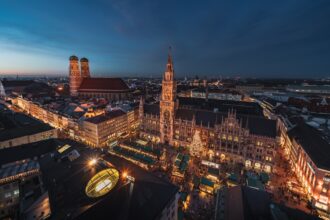 Evening view of Munich’s Marienplatz Christmas market with festive lights and wooden stalls.